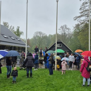 Groep mensen met paraplu's buiten, in een park op een regenachtige dag.
