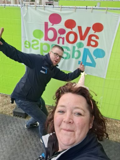 Twee mensen poseren enthousiast voor een kleurrijke banner met de tekst "Voad Aandacht".