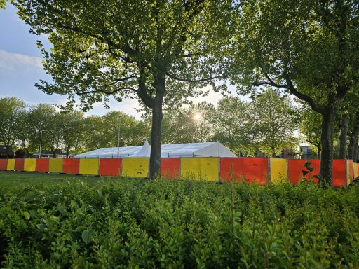 Een tent omringd door een gekleurde schutting tussen bomen in een park.